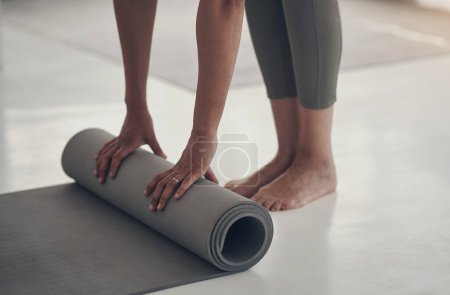 Téléchargez les photos : Ça a été une super séance de yoga. une femme méconnaissable enroulant son tapis de yoga après une séance d'entraînement dans son salon - en image libre de droit