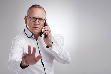 Photo for Shh, Im on the phone with my future self. a handsome mature businessman standing alone against a grey background in the studio and using his cellphone - Royalty Free Image
