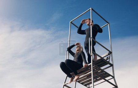 Téléchargez les photos : On devrait regarder de plus près. deux personnes portant une combinaison de plongée assis sur une tour de sauveteur - en image libre de droit
