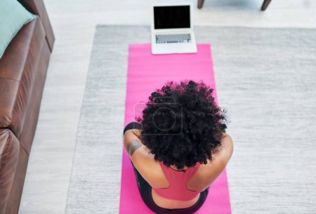Téléchargez les photos : Mon prof de yoga sera bientôt en direct. une jeune femme utilisant son ordinateur portable tout en pratiquant le yoga à la maison - en image libre de droit