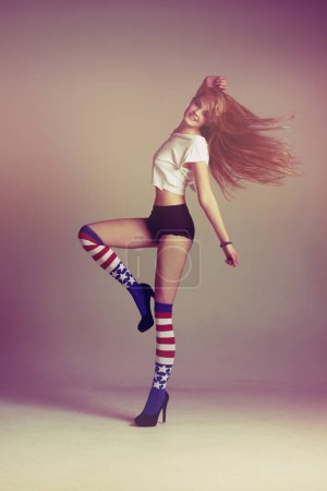 Téléchargez les photos : Portrait de femme avec chaussettes, mode et énergie dans un style d'art rétro sur fond de studio avec drapeau américain. Beauté, sous-vêtements et insouciant, modèle influenceur sexy sauter dans l'espace de maquette amusant vintage - en image libre de droit