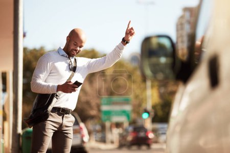 Photo for Trying to reply to texts and hail a ride. a handsome young businessman hailing a ride in the city - Royalty Free Image