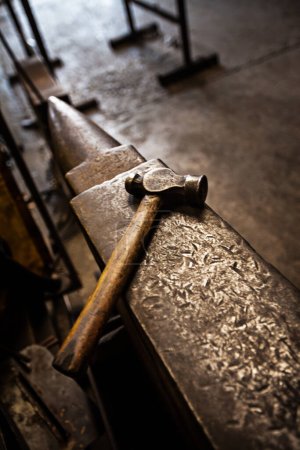Photo for Hammer, anvil and blacksmith workplace in a iron factory and industrial workshop. Tools, metal work and steel artisan bench with craftmanship equipment to forge in warehouse with metals and materials. - Royalty Free Image