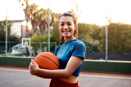 Foto de El baloncesto me hace feliz. una joven deportista atractiva parada en la cancha sola y sosteniendo una pelota de baloncesto durante el día - Imagen libre de derechos