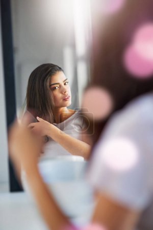 Foto de ¿Cómo debo peinarme hoy? una hermosa mujer joven cepillándose el pelo en el baño en casa - Imagen libre de derechos