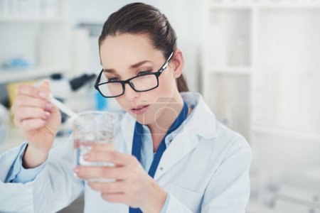 Téléchargez les photos : Qu'est-ce qu'on a là ? une jeune scientifique concentrée mélangeant des produits chimiques à leur bureau dans un laboratoire - en image libre de droit