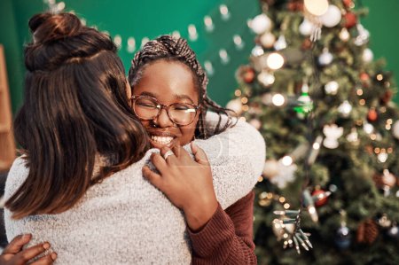 Foto de Si algo inspira unión, es Navidad. dos mujeres jóvenes felices abrazándose durante la Navidad en casa - Imagen libre de derechos