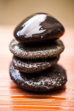 Photo for Stones, zen and wet rocks for hot stone massage at a spa for luxury and wellness. Peace, closeup and rock balance with tranquility and feng shui for meditation, holistic therapy and water on pile. - Royalty Free Image