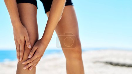 Photo for Pain is only temporarily. a woman holding on to her injured knee while out for a run - Royalty Free Image