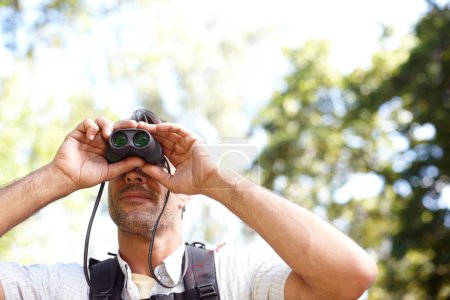 Foto de Obteniendo una mejor vista. Un joven mirando algo a través de sus prismáticos - Imagen libre de derechos