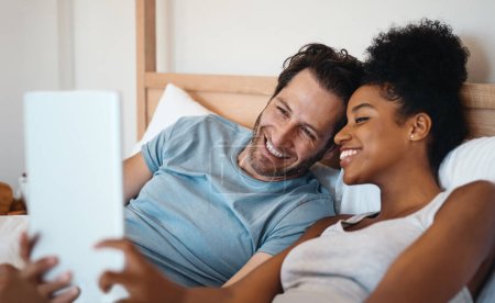 Photo for Happy couple, smile and relax on bed for selfie, photo or morning post together at home. Interracial man and woman person smiling for fun profile picture, memory or vlog in bedroom at the house. - Royalty Free Image