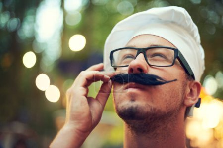 Foto de Le Oui. Un hombre ajustando su bigote falso mientras usa gafas y una boina - Imagen libre de derechos