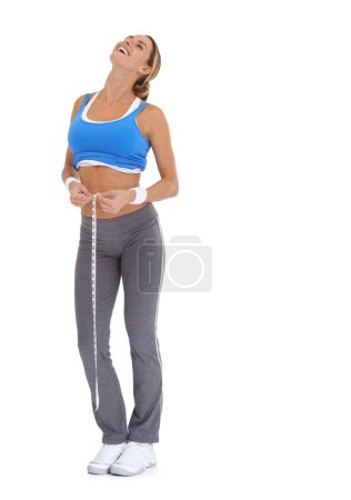 Foto de Perder pulgadas y sentirse bien. Mujer joven en ropa deportiva midiendo su cintura mientras está aislada en blanco - Imagen libre de derechos