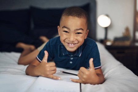 Photo for Im feeling awesome. an adorable little boy lying on his bed with a book and pencil - Royalty Free Image