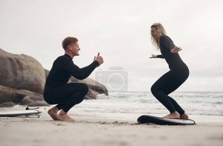 Photo for I think youre ready to catch some waves. a man giving a woman surfing lessons on the beach - Royalty Free Image