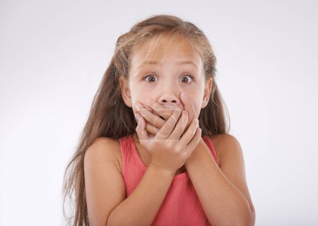 She cant believe it. Portrait of a little girl covering her mouth in disbelief