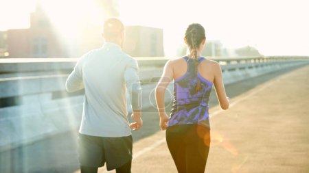 Photo for Running through the sunrise. Rearview shot of two friends jogging through the city - Royalty Free Image