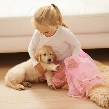 Photo for Child, golden retriever or dog playing together in a happy home with love, care and development. Girl kid and animal, puppy or pet in a tutu for dress up game as friends on the living room floor. - Royalty Free Image