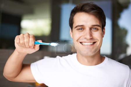 Foto de Cepillarse los dientes, retrato de hombre y limpieza en un baño en casa para la higiene bucal y la salud. Sonrisa, dental y cepillo de dientes con una persona masculina con felicidad en la mañana en una casa con cuidado. - Imagen libre de derechos