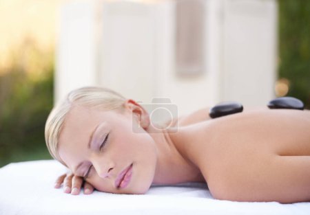 Téléchargez les photos : Femme se faire masser aux pierres chaudes dans un spa avec bien-être, guérison et traitement holistique au complexe de luxe. Soulagement du stress, zen et femme avec des pierres sur le dos pour l'autosoin et la physiothérapie. - en image libre de droit