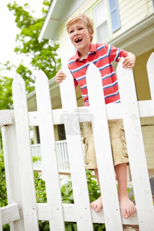 Photo for Bye dad. A happy young boy standing on his fence and saying goodbye to his dad - Royalty Free Image