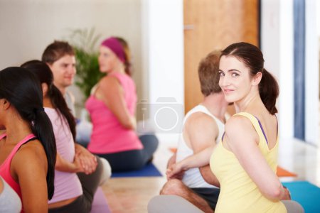 Foto de Disfrutando de una clase de yoga. Retrato de una mujer feliz sentada y haciendo estiramientos durante una clase de yoga - Imagen libre de derechos