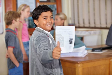 Photo for Portrait, child and student with thumbs up and paper for test or assignment in classroom. Happiness, hand gesture and kid with like emoji, agreement and learning in elementary school for education - Royalty Free Image