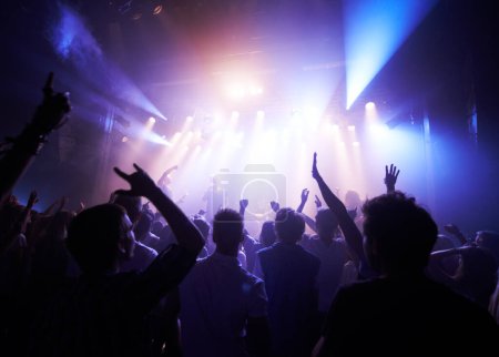 Foto de Music, dance and party with crowd at concert for rock, live band performance and festival show. New year, celebration and disco with audience of fans listening to techno, rave and nightclub event. - Imagen libre de derechos
