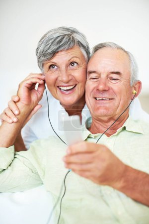 Foto de Alegre pareja madura escuchando música. Alegre pareja madura escuchando música en casa - Imagen libre de derechos
