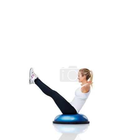 Shes increasing her core strength through balance. An attractive young woman balancing on a bosu-ball while working out