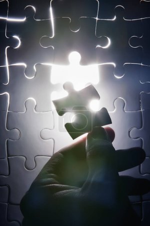 Photo for Hand, missing jigsaw puzzle and glow with light for problem solving, ideas and connection. Person, brain power and games with strategy, innovation or synergy for solution, link or creativity for goal. - Royalty Free Image