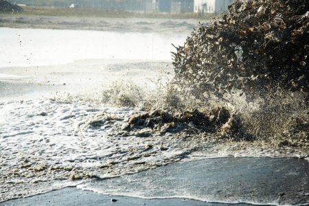 Téléchargez les photos : Pollution, égouts et déchets dans l'eau à l'océan de l'industrie pour la construction, pipeline et danger. Environnement, texture et industrie avec vague d'eaux usées sur le rivage pour ruisseau, mousse et boue. - en image libre de droit