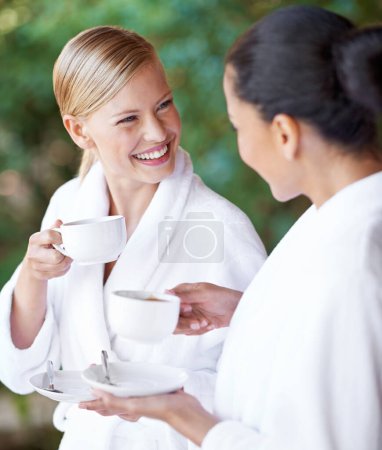 Téléchargez les photos : Même le café est relaxant. Deux jeunes femmes prenant un café dans leurs peignoirs au spa de jour - en image libre de droit