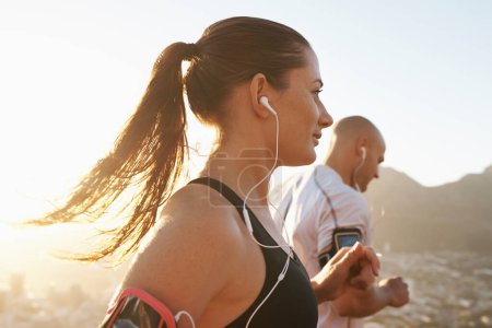 Photo for Streaming, fitness and running couple doing exercise or morning workout for health and wellness together. Sport, man and woman runner run with athlete while training and listening to sports music. - Royalty Free Image
