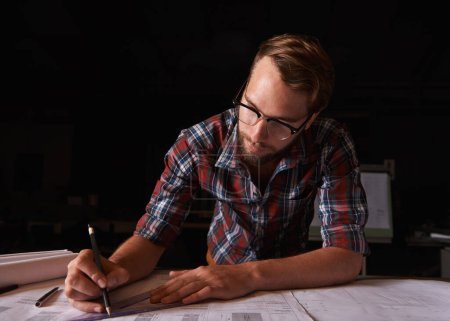 Photo for He desired to make the world beautiful. a young man sitting indoors working on building plans - Royalty Free Image