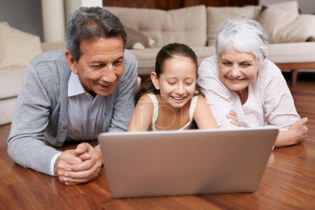 Photo for Laptop, floor or grandparents with girl for movie streaming online subscription in retirement at home together. Child, relaxing or happy grandmother loves watching fun videos with a senior old man. - Royalty Free Image