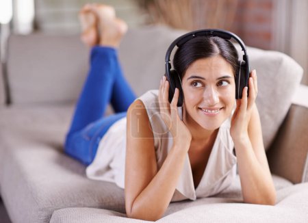 Photo for Happy woman, headphones and listening to music on sofa for thinking, comfort or relaxing at home. Female lying on living room couch with headset for audio sound track or relax on holiday break. - Royalty Free Image