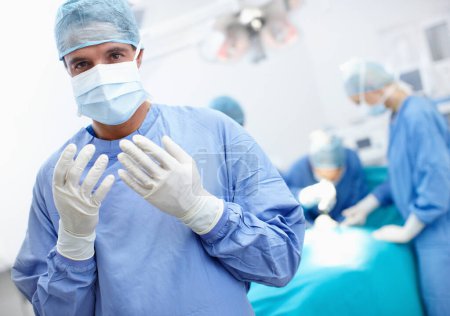 Foto de Lista para ir a trabajar. Vista inclinada de un cirujano con guantes quirúrgicos en un quirófano - Imagen libre de derechos