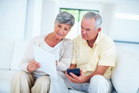 Téléchargez les photos : Couple d'âge mûr calculant les factures. Couple d'âge mûr calculant les factures domestiques dans le salon - en image libre de droit