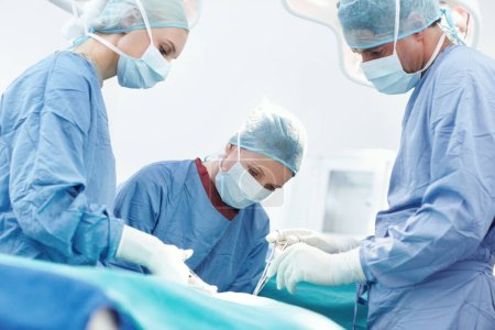 Photo for A stitch in time. Surgeons using medical tools and forceps to operate on a patient in surgery - Royalty Free Image