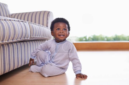 Photo for Black baby boy sitting on floor in living room, childhood development with growing happy kid at family home. African male toddler, cute child relax on wood floor with growth and learning mobility. - Royalty Free Image