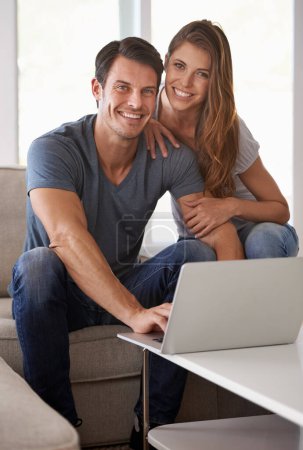 Téléchargez les photos : Heureux à la maison. Portrait d'un jeune couple affectueux assis avec un ordinateur portable à l'intérieur - en image libre de droit