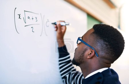 Téléchargez les photos : Résoudre l'équation. un jeune homme écrivant sur un tableau blanc dans une classe - en image libre de droit