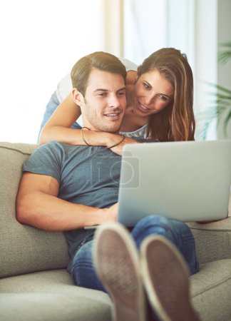 Photo for Couple, laptop and hug on home sofa while on internet for remote work or streaming movies. A man and woman together in a house while happy about online shopping, search or internet connection. - Royalty Free Image