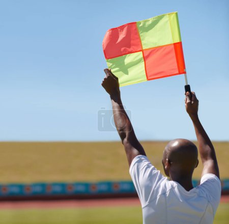 Photo for Flag, foul and man soccer referee in football match or game wave to stop play during sport training or workout. Hand, sports and person or assistant official raise or signal mistake in sky background. - Royalty Free Image