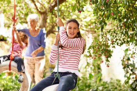 Photo for Young girl, garden and grandma playing with grandkid on background or holidays, having fun on a tyre swing in summer. Excited, grandchildren and outdoors on jungle gym or on sunny portrait at a park. - Royalty Free Image