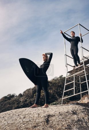 Photo for The search for the perfect wave is on. two people pointing at something while standing by a lifeguard tower - Royalty Free Image