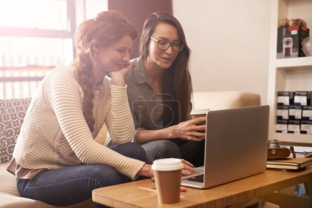 Photo for Technology brings friends closer. two friends using a laptop in a coffee shop - Royalty Free Image