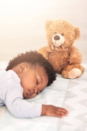 Foto de Durmiendo, osito de peluche y cansado con bebé en el dormitorio por despreocupación, desarrollo e inocencia. Soñar, relajarse y cómodo con el bebé africano y el juguete en casa para la mañana, el descanso y la hora de dormir. - Imagen libre de derechos