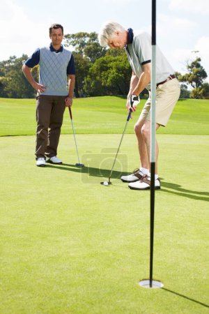 Foto de Sintiendo la presión de ese agujero final. Dos hombres en el green jugando una ronda de golf juntos - Imagen libre de derechos
